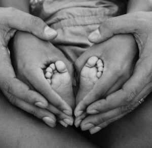 manos del padre y la madre entrelazando los pies de su hijo